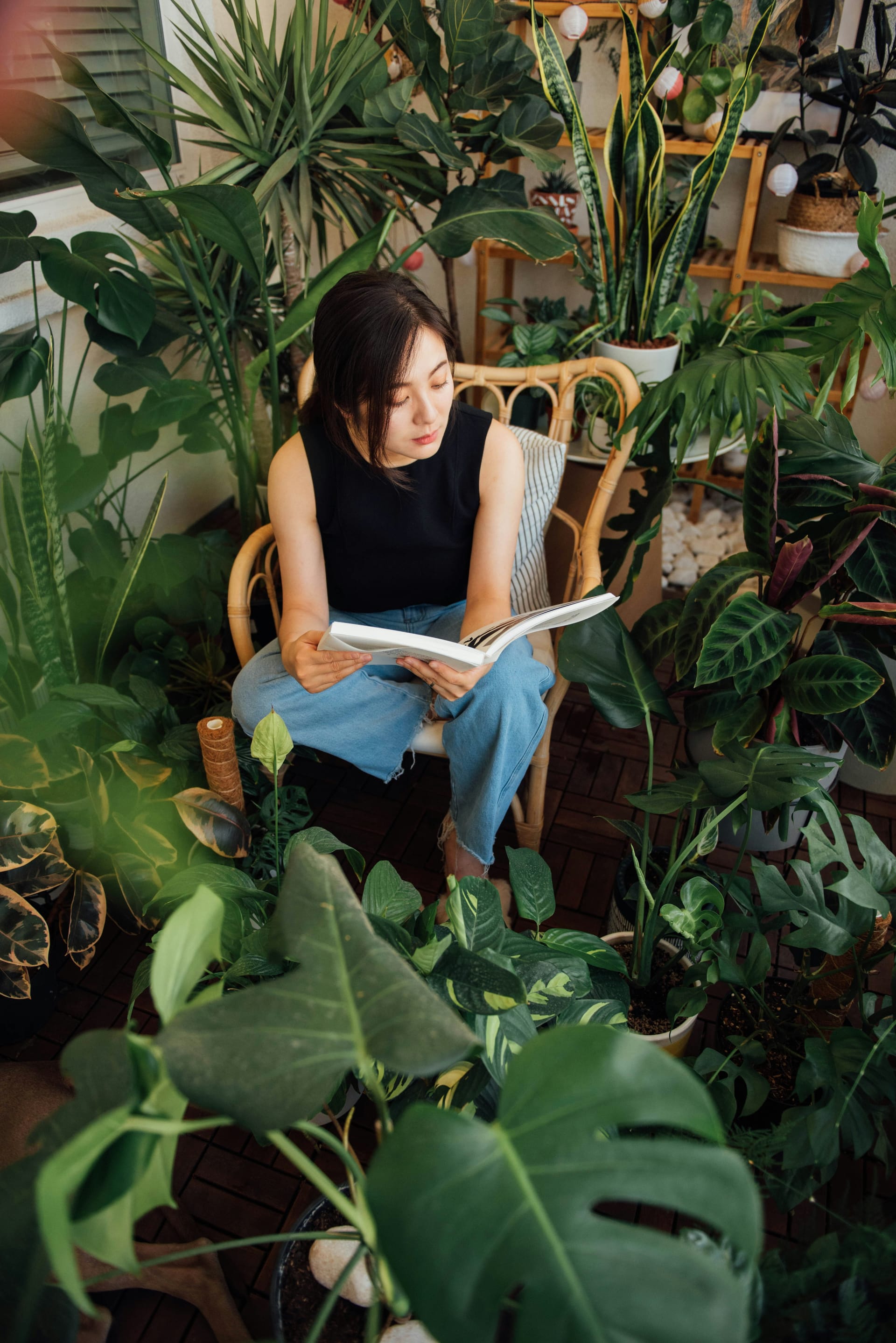 A person reading a book surrounded by lush green plants